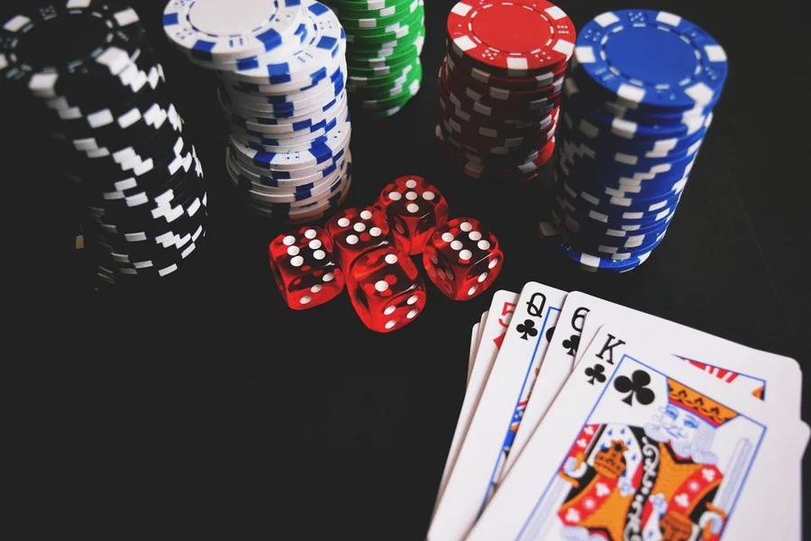 Stacks of casino chips, dice and playing cards on a dark table