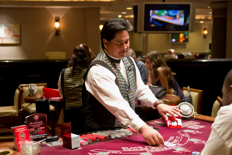 A croupier dealing at a casino table while players watch