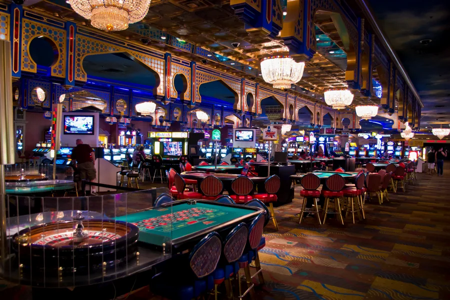 A casino floor: roulette tables in front, machine banks behind