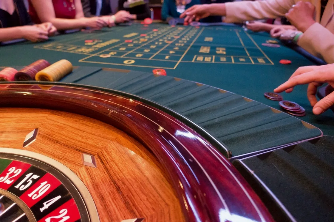 Players at a roulette table, chips down on the layout